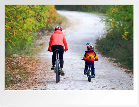Adult and child riding bikes down a path