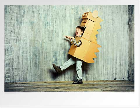 Boy pretending to be a dinosaur in a cardboard box